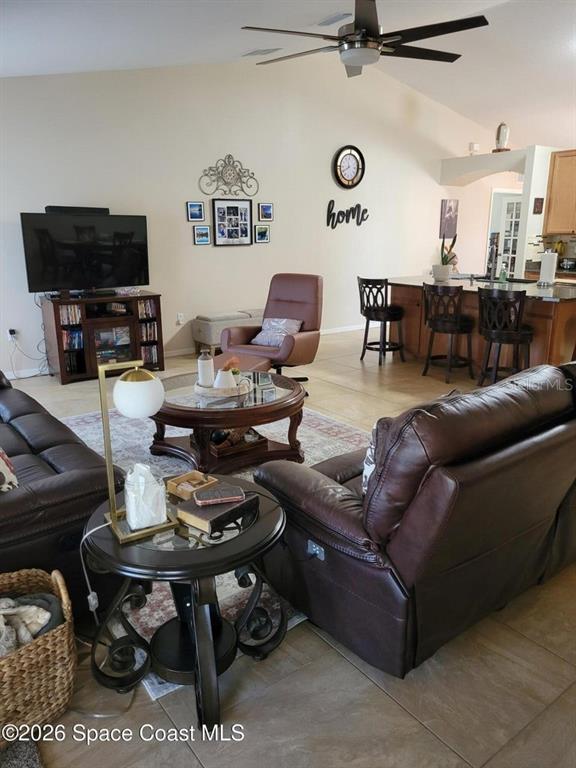 This open-concept living room features brown leather furniture, a coffee table, and a kitchen island — 1703 VALCOURT STREET NW, PALM BAY, FL