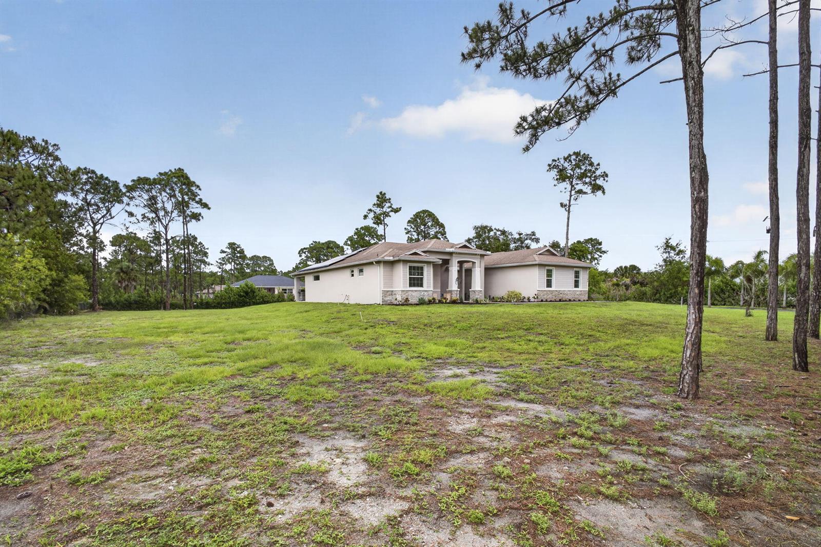 A single-story house with a beige exterior sits on a large, grassy, partially wooded lot — 17145 Hamlin Boulevard, Loxahatchee FL 33470, LOXAHATCHEE, FL