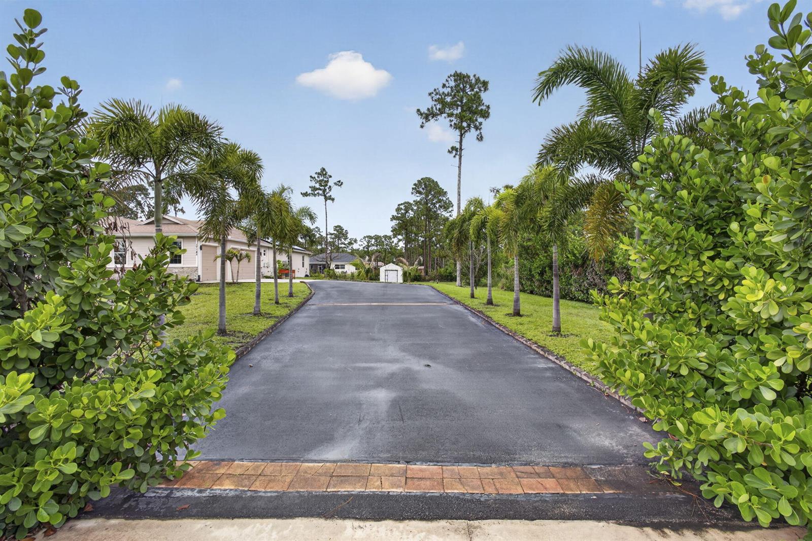 A paved driveway leads toward a house and shed, flanked by palm trees and greenery — 17145 Hamlin Boulevard, Loxahatchee FL 33470, LOXAHATCHEE, FL