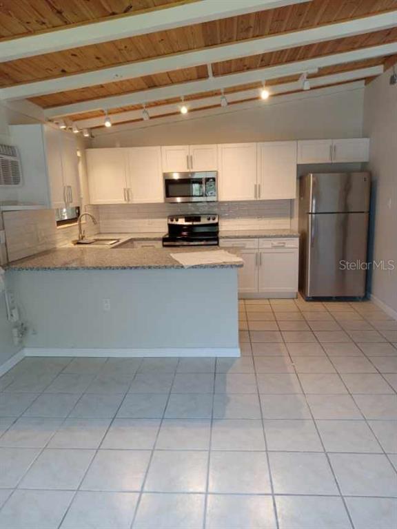 A kitchen with white cabinets, granite countertops, stainless steel appliances, and a wood-beamed ceiling — 1117 PATTERSON DRIVE UNIT Front, SARASOTA, FL