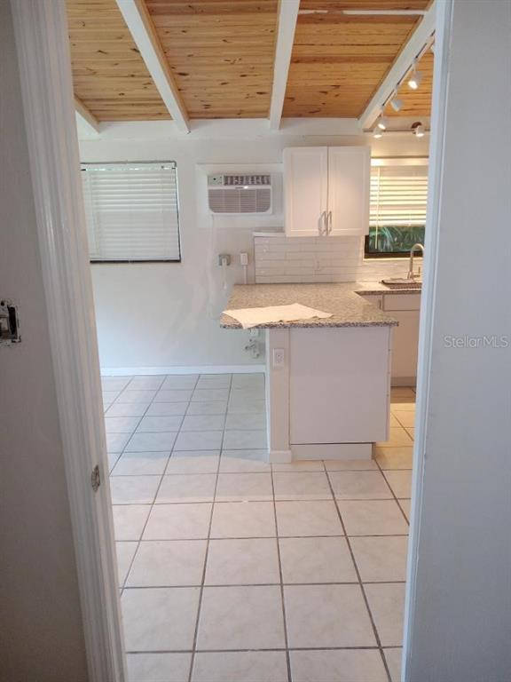 A kitchen features white cabinets, granite countertops, tile flooring, and a wood-paneled ceiling — 1117 PATTERSON DRIVE UNIT Front, SARASOTA, FL