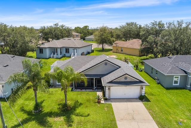 An aerial view shows a suburban house with a two-car garage and palm trees — 1816 MANITOBA COURT, KISSIMMEE, FL