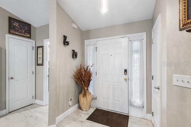 This entryway features a white front door, light-colored walls, and tile flooring — 1816 MANITOBA COURT, KISSIMMEE, FL