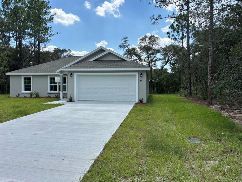 A single-story house with a gray exterior, a white garage door, and a concrete driveway — 8468 N EMPIRE AVENUE, DUNNELLON, FL