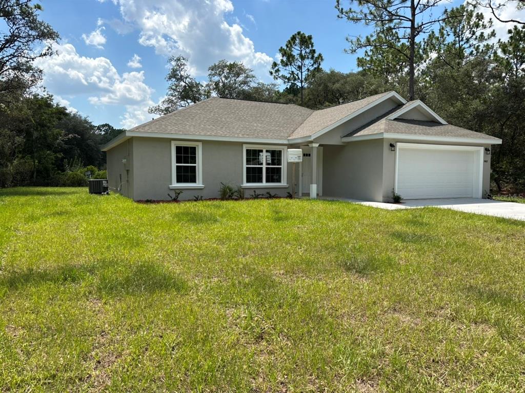 A single-story house with a beige stucco exterior, a two-car garage, and a grassy yard — 8468 N EMPIRE AVENUE, DUNNELLON, FL