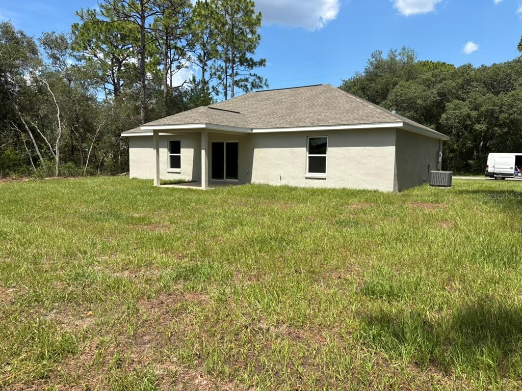 The exterior rear view of a single-story house features a covered patio and lawn — 8468 N EMPIRE AVENUE, DUNNELLON, FL
