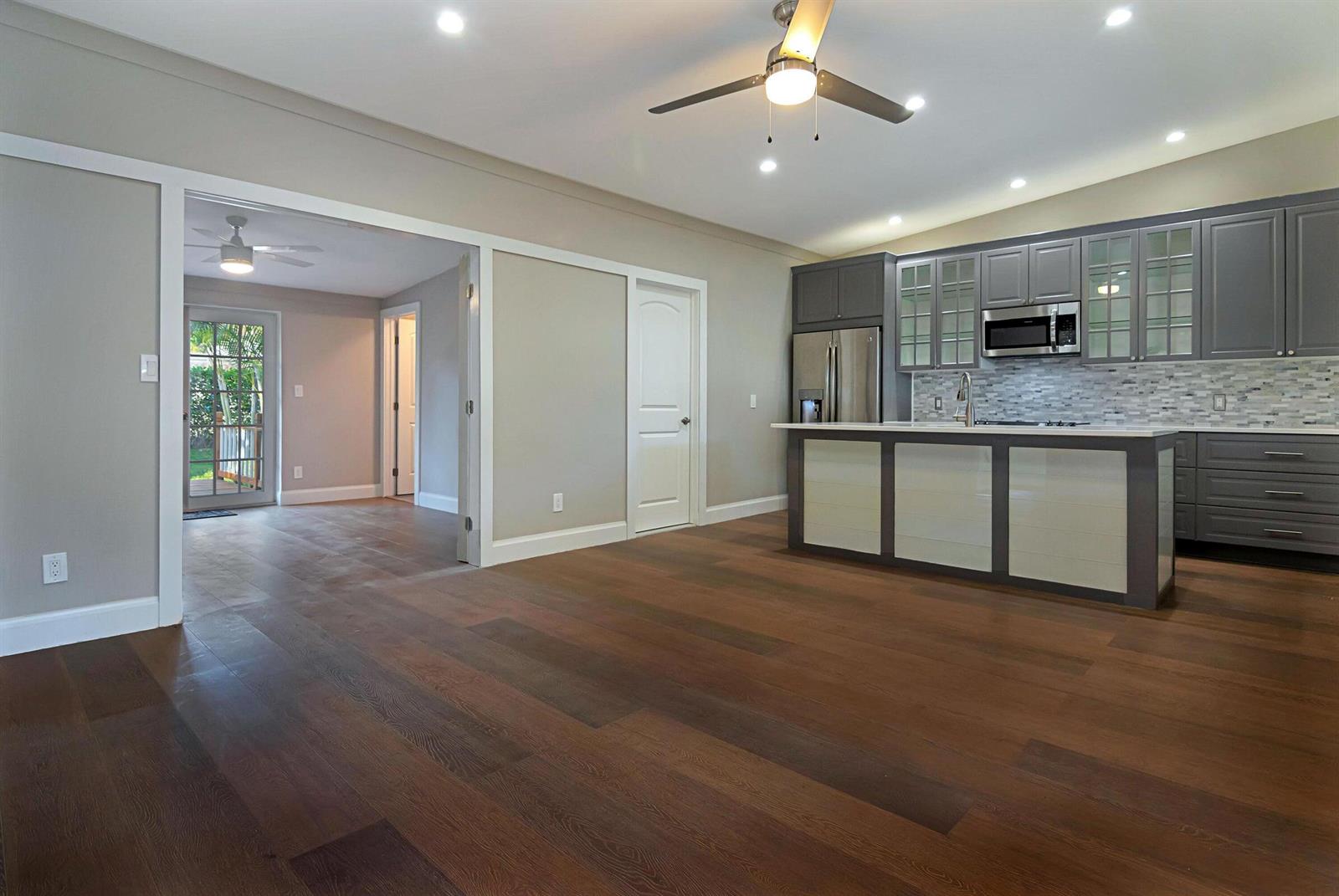 A kitchen with gray cabinets and a center island opens into a living area — 959 SW 18th Street, Boca Raton FL 33486, BOCA RATON, FL