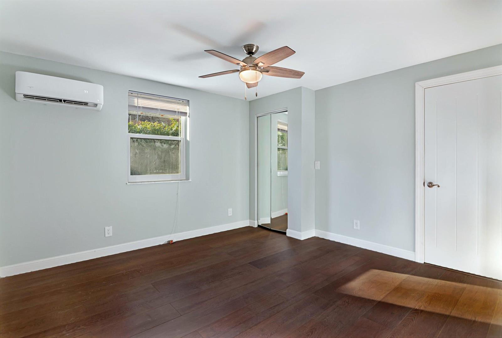 An empty bedroom features light blue walls, dark wood flooring, a ceiling fan, and a mini-split — 959 SW 18th Street, Boca Raton FL 33486, BOCA RATON, FL