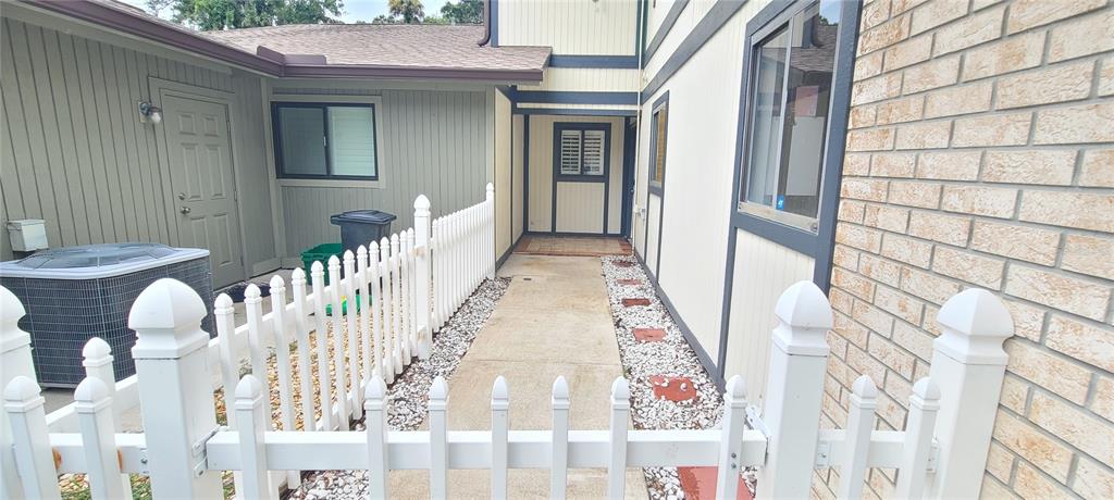 A white picket fence encloses a concrete walkway leading to the entrance of a house — 836 SUGAR HOUSE DRIVE, PORT ORANGE, FL
