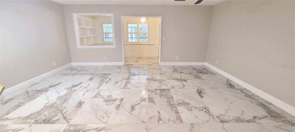 A room with light gray walls and large, polished marble-patterned floor tiles — 836 SUGAR HOUSE DRIVE, PORT ORANGE, FL