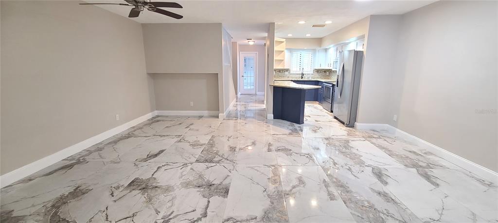 An open-concept living area features large-format marble-look tile flooring and a kitchen with dark cabinetry — 836 SUGAR HOUSE DRIVE, PORT ORANGE, FL