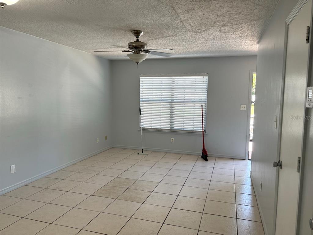An empty room with light-colored tile flooring, a ceiling fan, and a window with blinds — 2302 MAKI ROAD UNIT 25, PLANT CITY, FL