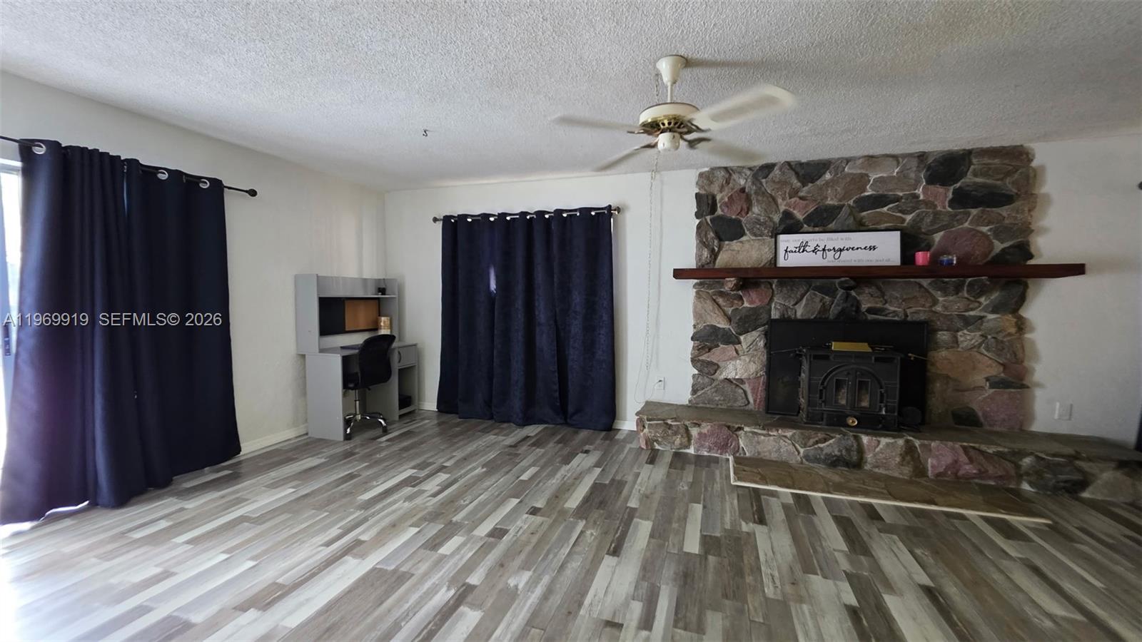A living room features a stone fireplace, wood-look flooring, and a desk area — 18227 BRANCH ROAD, Hudson FL 34667, HUDSON, FL