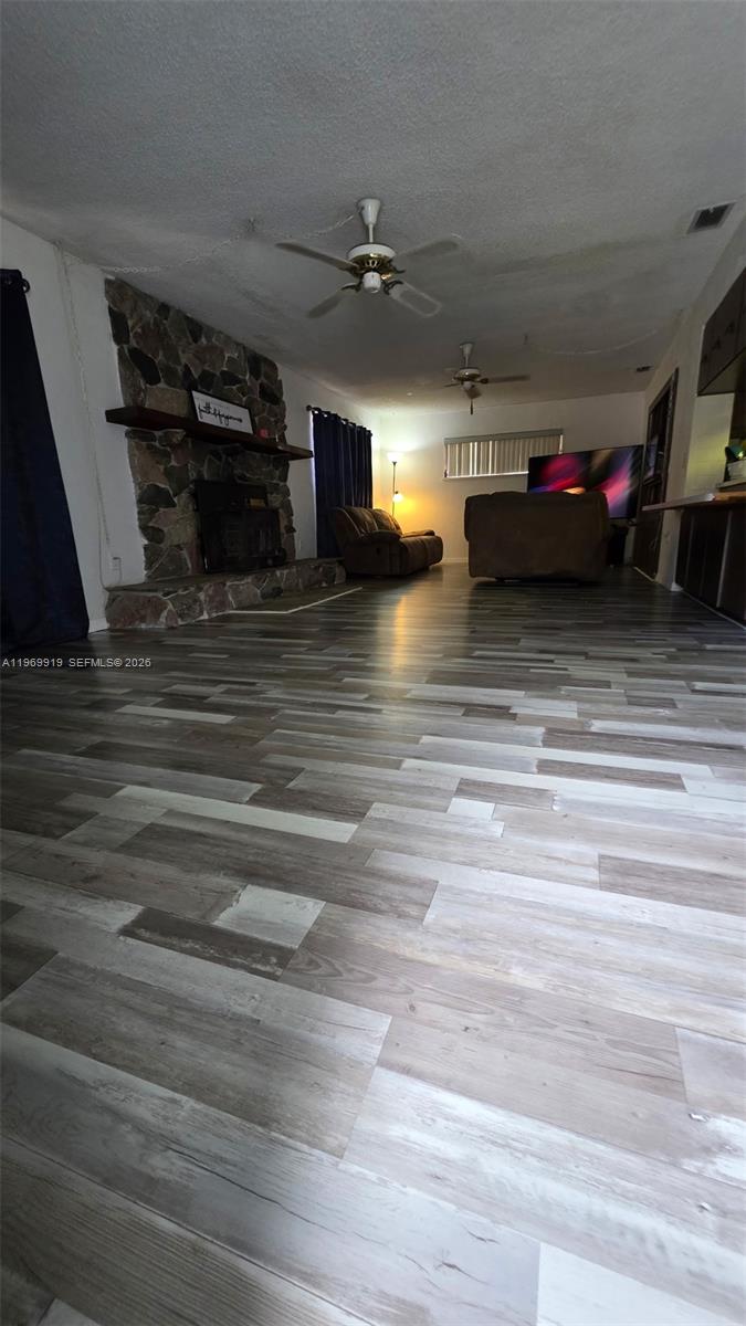 A living room features a stone fireplace, wood-look flooring, and two ceiling fans — 18227 BRANCH ROAD, Hudson FL 34667, HUDSON, FL