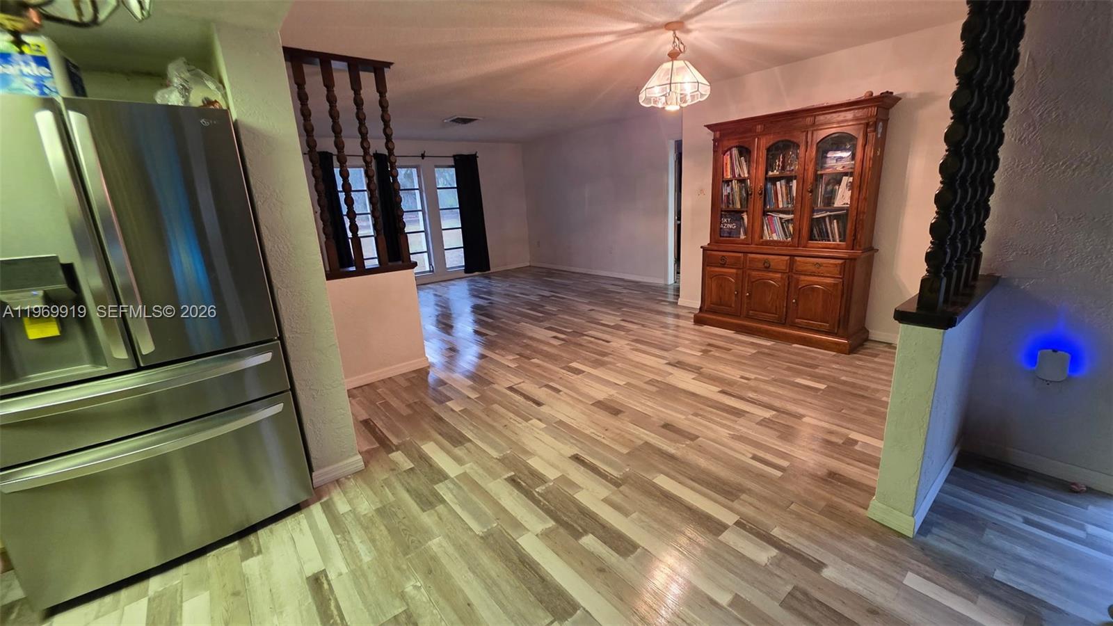 A dining area features wood-look laminate flooring, a wooden hutch, and a stainless steel refrigerator — 18227 BRANCH ROAD, Hudson FL 34667, HUDSON, FL
