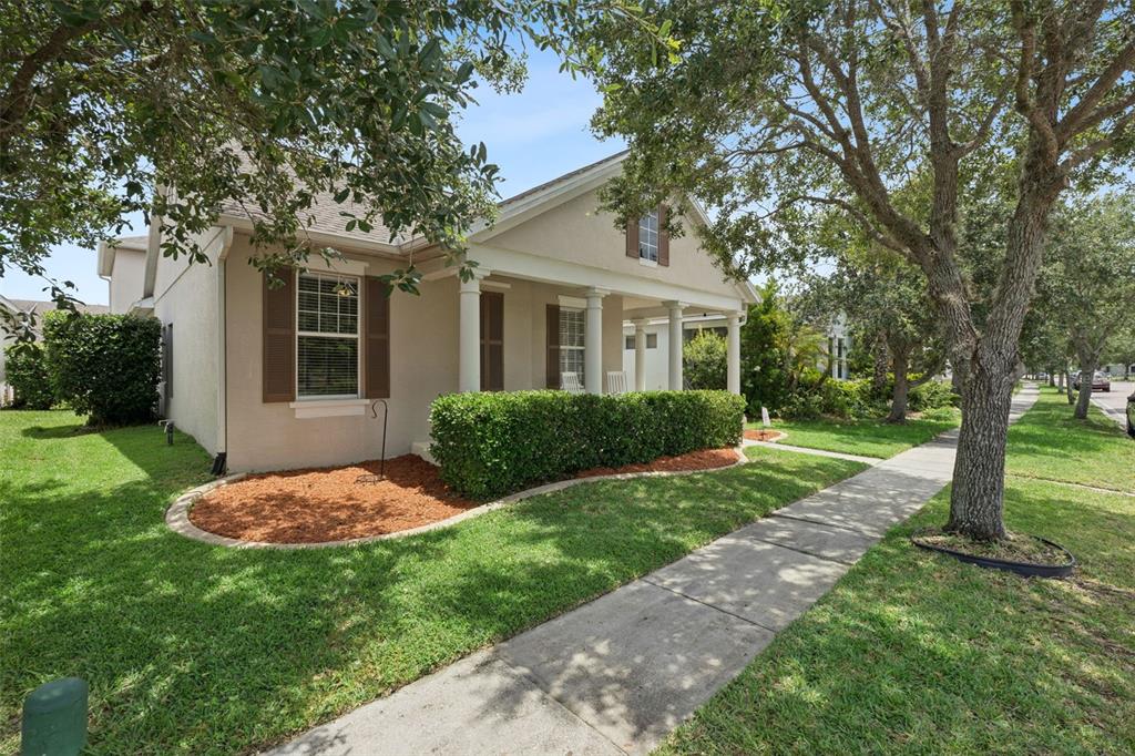 A single-story house with a covered front porch, brown shutters, and a manicured hedge — 14011 GOLDEN RAIN TREE BOULEVARD, ORLANDO, FL