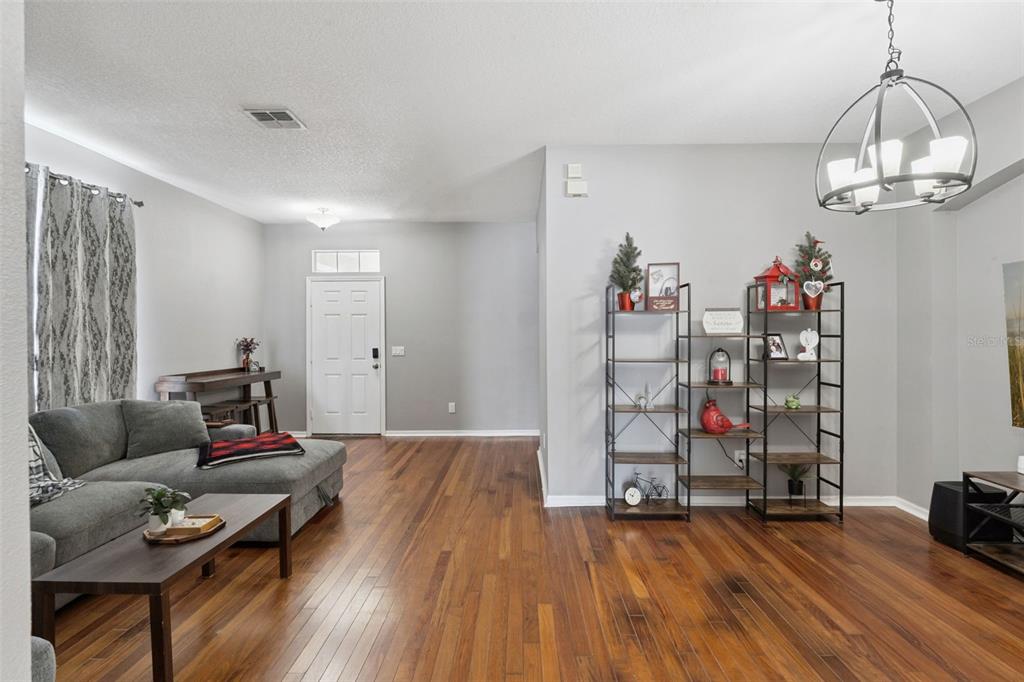 A living room features hardwood floors, a gray sectional sofa, and two tall metal shelves — 14011 GOLDEN RAIN TREE BOULEVARD, ORLANDO, FL