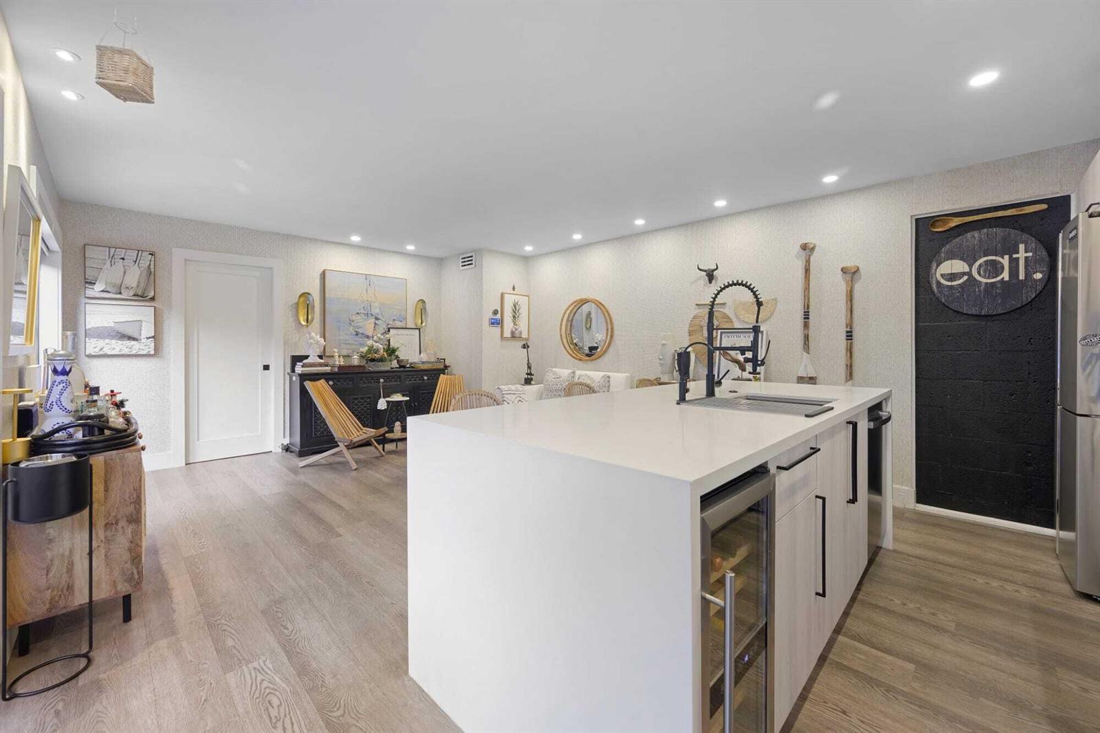 A modern kitchen features a white quartz island, light wood flooring, and a black accent wall — 1605 S Us Highway 1 # 10c, Jupiter FL 33477, JUPITER, FL
