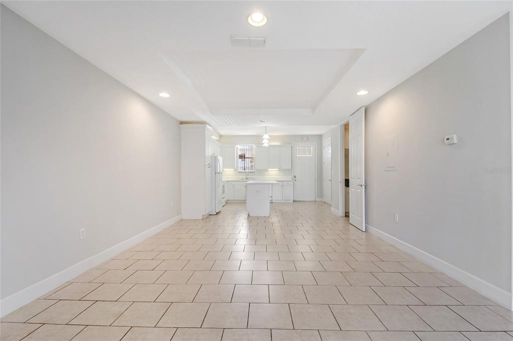 A kitchen with white cabinetry and a central island opens into a tiled dining area — 608 CORNERSTONE DRIVE, KISSIMMEE, FL