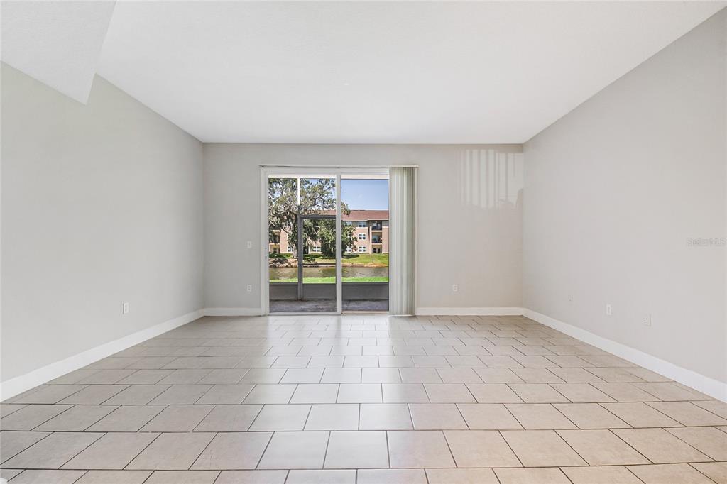 An empty room with light-colored tile flooring and a sliding glass door leading to a balcony — 608 CORNERSTONE DRIVE, KISSIMMEE, FL