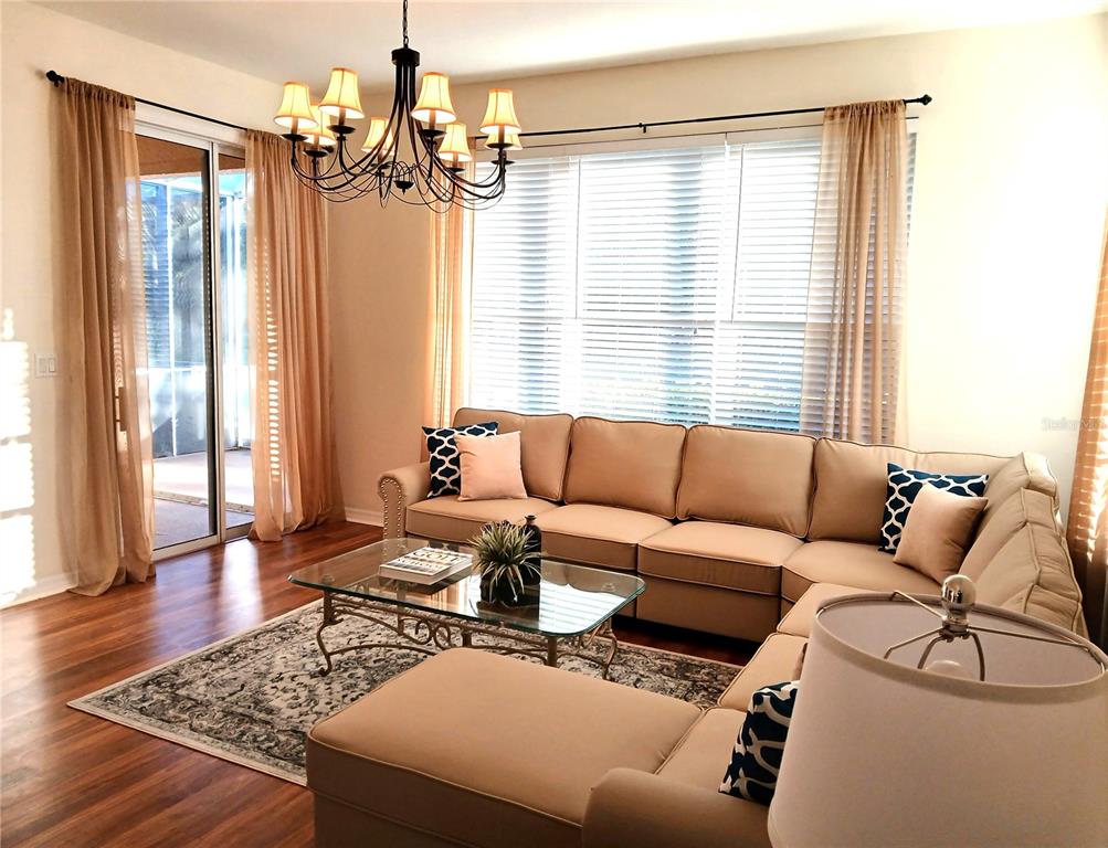 A living room features a tan sectional sofa, a glass coffee table, and a chandelier — 5641 HIDDEN OAK COURT, NORTH PORT, FL