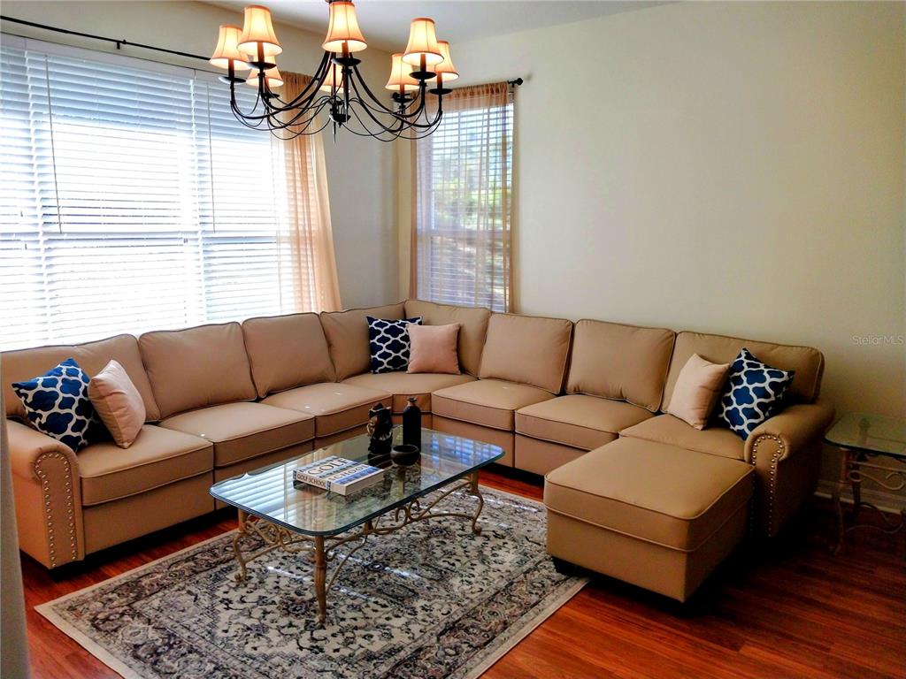 A living room features a large tan sectional sofa, a glass coffee table, and a chandelier — 5641 HIDDEN OAK COURT, NORTH PORT, FL