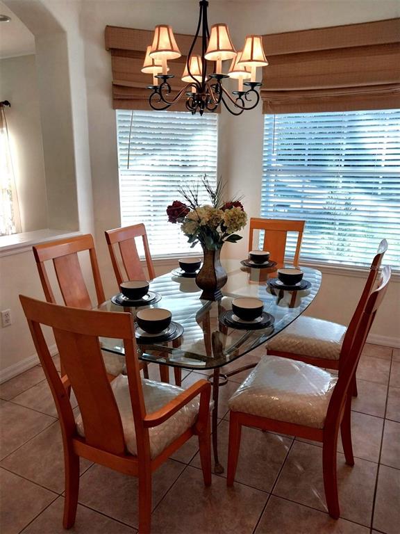 A dining room features a glass-topped table, wooden chairs, and a decorative chandelier — 5641 HIDDEN OAK COURT, NORTH PORT, FL