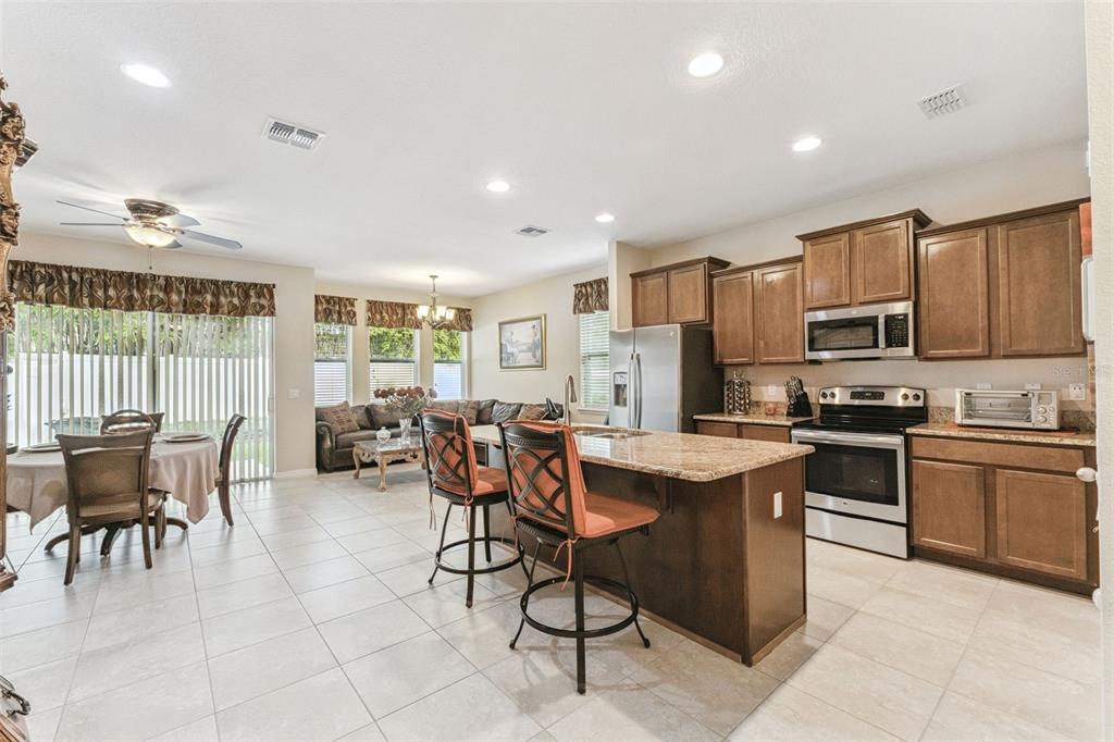 An open-concept kitchen and living area features wood cabinets, granite countertops, and tile flooring — 1224 PETERSON PLACE, SANFORD, FL
