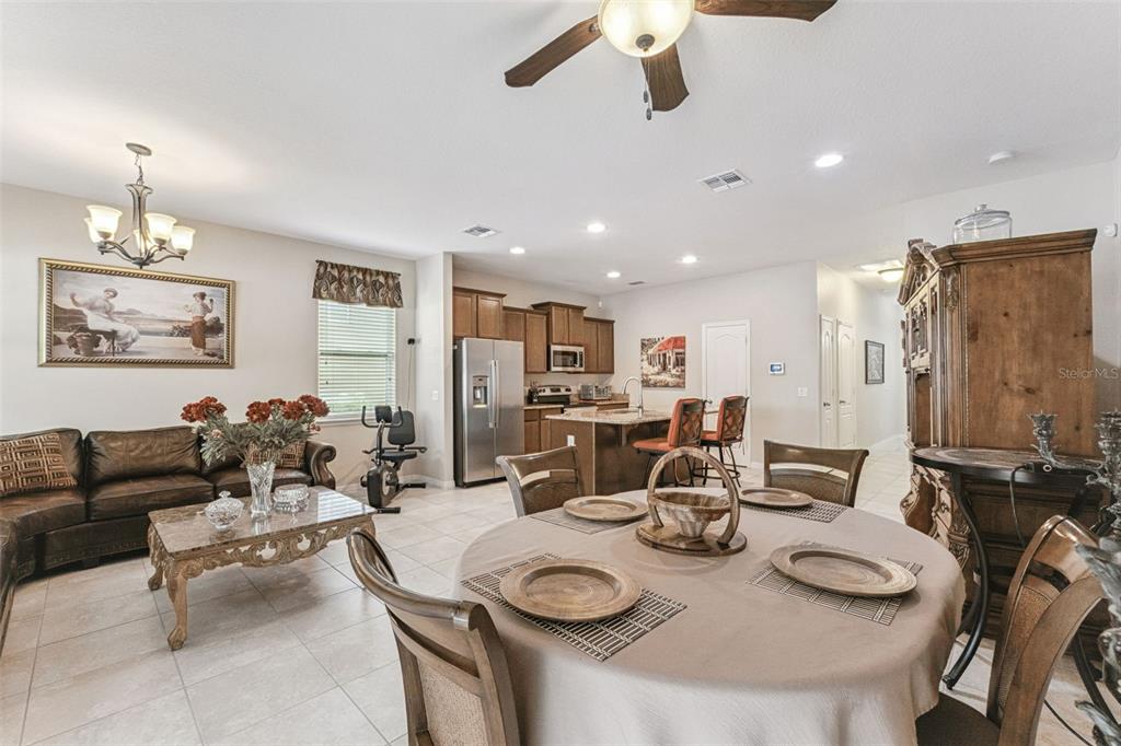 An open-concept living and dining area features tile flooring, a kitchen island, and wooden furniture — 1224 PETERSON PLACE, SANFORD, FL