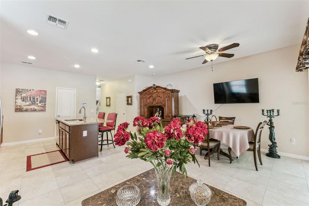 An open-concept kitchen and dining area featuring tile flooring, a kitchen island, and wood furniture — 1224 PETERSON PLACE, SANFORD, FL
