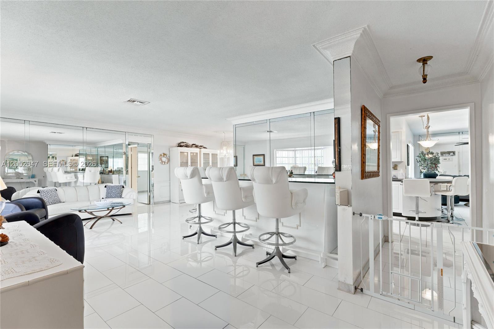 A bright, white-tiled living area features a mirrored wet bar with three modern stools — 8 Castle Harbor Is, Fort Lauderdale FL 33308, FORT LAUDERDALE, FL
