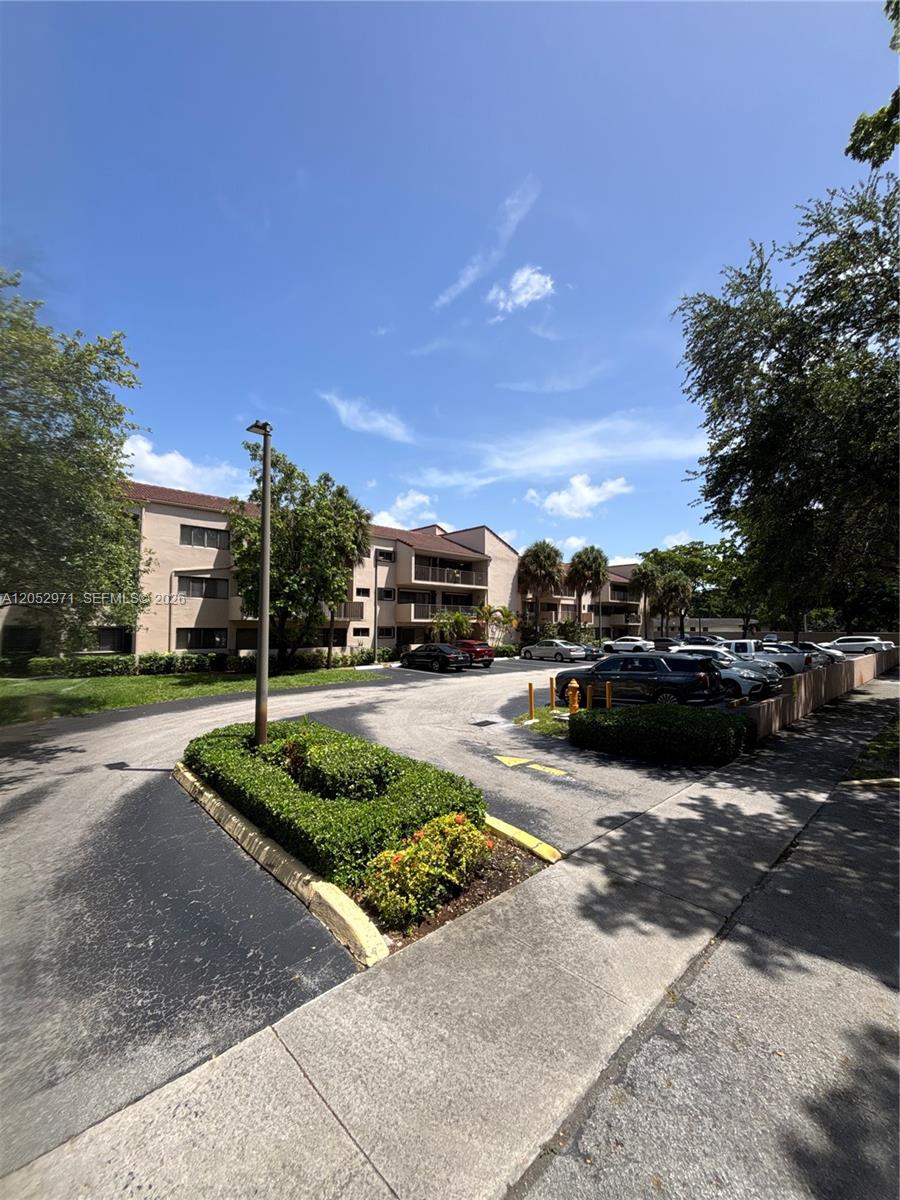 A multi-story apartment building exterior features a parking lot with several parked cars — 6305 Gage Pl # 309A, Miami Lakes FL 33014, MIAMI LAKES, FL