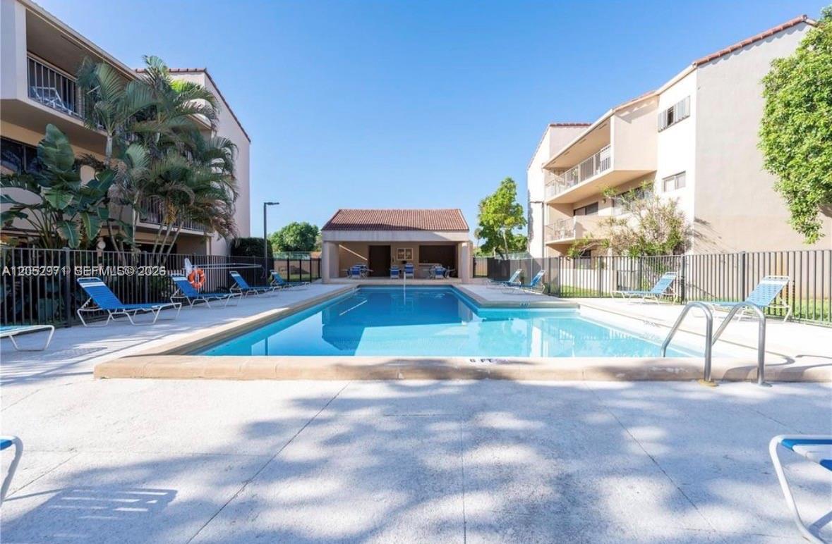 An outdoor swimming pool is situated between two multi-story apartment buildings with lounge chairs — 6305 Gage Pl # 309A, Miami Lakes FL 33014, MIAMI LAKES, FL