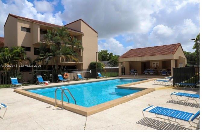 A swimming pool sits in front of a multi-story apartment building and a covered patio — 6305 Gage Pl # 309A, Miami Lakes FL 33014, MIAMI LAKES, FL