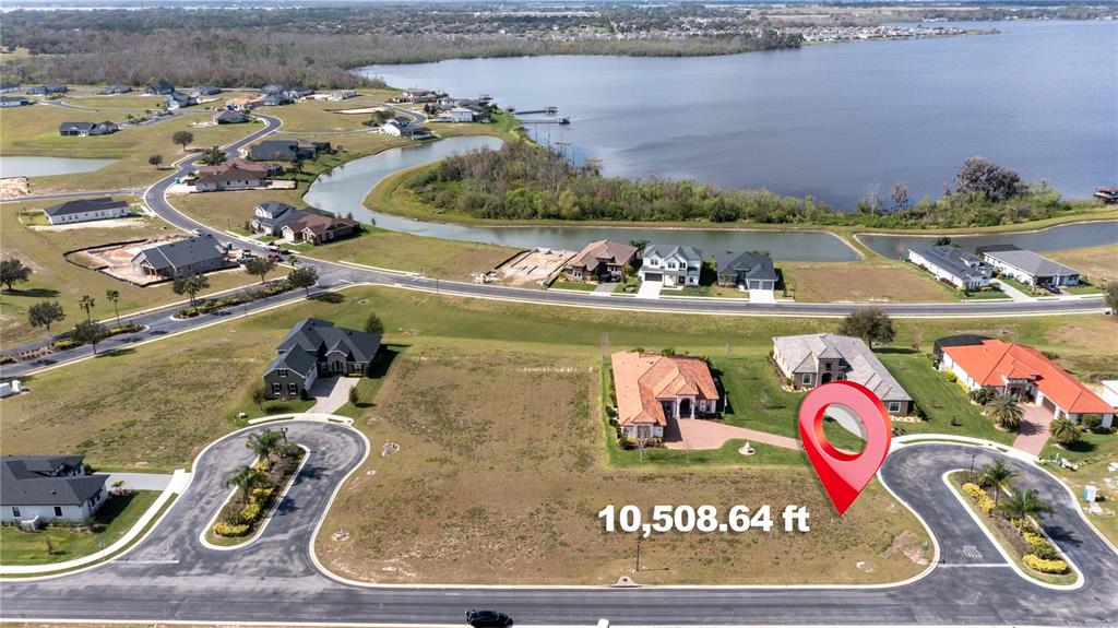 An aerial view shows a vacant residential lot next to two houses near a lake — 599 LOBLOLLY PLACE, AUBURNDALE, FL