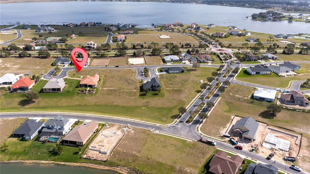 This aerial view shows a residential neighborhood with several houses and vacant lots near water — 599 LOBLOLLY PLACE, AUBURNDALE, FL