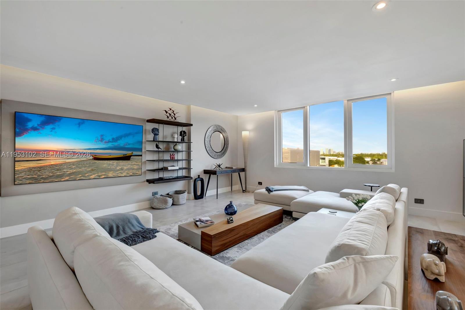 A modern living room features a large sectional sofa, a wall-mounted television, and floor-to-ceiling windows — 2301 Collins Ave, Miami Beach FL 33139, MIAMI BEACH, FL