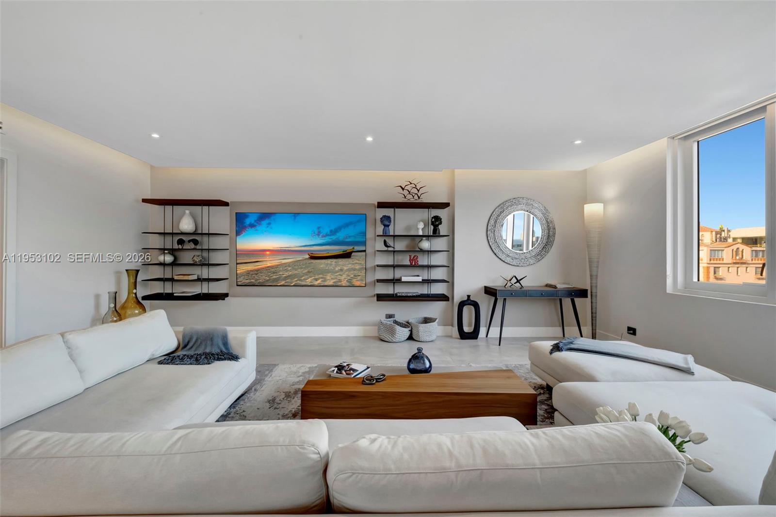 A modern living room features a large television, floating shelves, and white sectional sofas — 2301 Collins Ave, Miami Beach FL 33139, MIAMI BEACH, FL