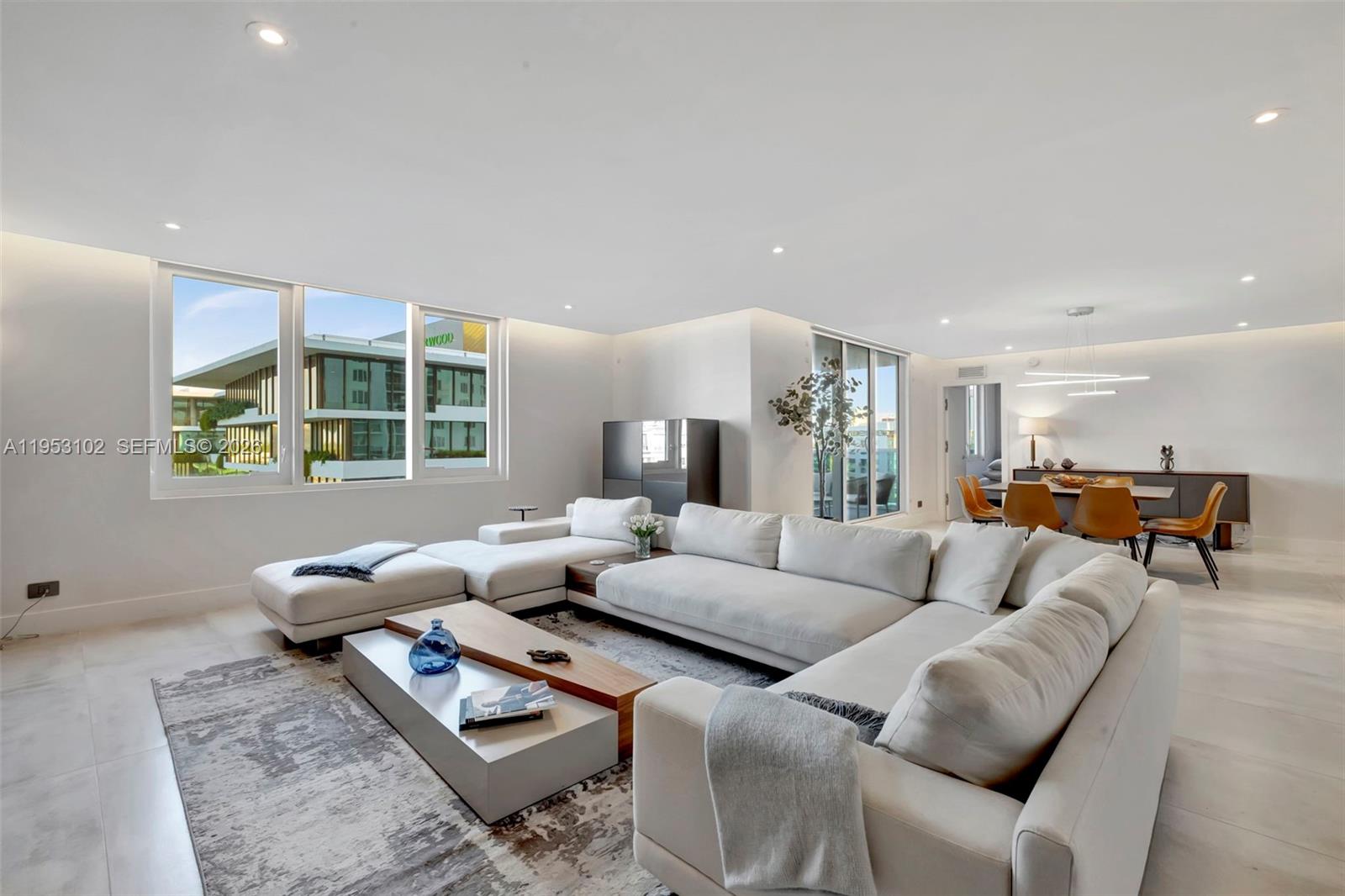 A modern living room features a large white sectional sofa, a coffee table, and dining area — 2301 Collins Ave, Miami Beach FL 33139, MIAMI BEACH, FL
