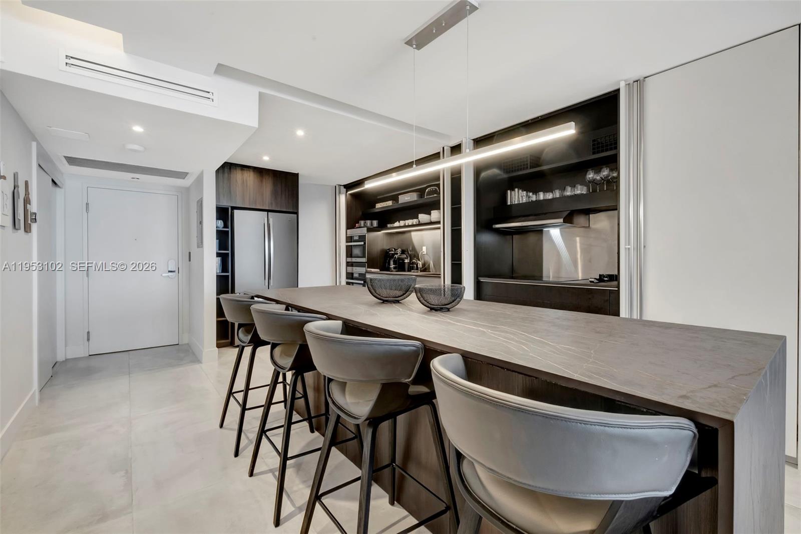 A modern kitchen features a long stone island with bar seating and dark cabinetry — 2301 Collins Ave, Miami Beach FL 33139, MIAMI BEACH, FL