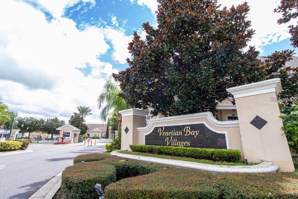 A large sign for Venetian Bay Villages stands in front of a gated community entrance — 2212 SAN VITTORINO CIRCLE UNIT 28-107, KISSIMMEE, FL