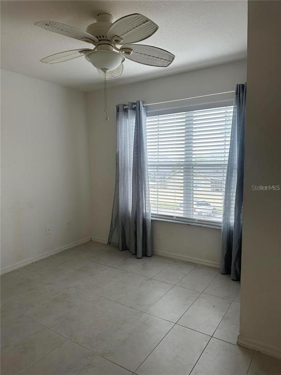 An empty room features light-colored tile flooring, a ceiling fan, and a window with blinds — 2212 SAN VITTORINO CIRCLE UNIT 28-107, KISSIMMEE, FL