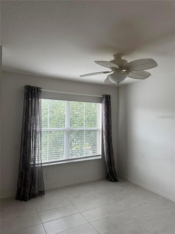 A room with white walls, tile flooring, a ceiling fan, and a window with curtains — 2212 SAN VITTORINO CIRCLE UNIT 28-107, KISSIMMEE, FL