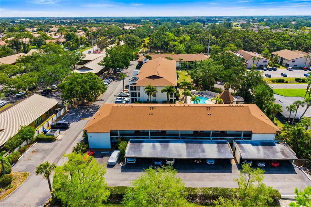 An aerial view shows a multi-story apartment building with a brown roof and covered parking — 7201 CURTISS AVENUE UNIT 2D, SARASOTA, FL