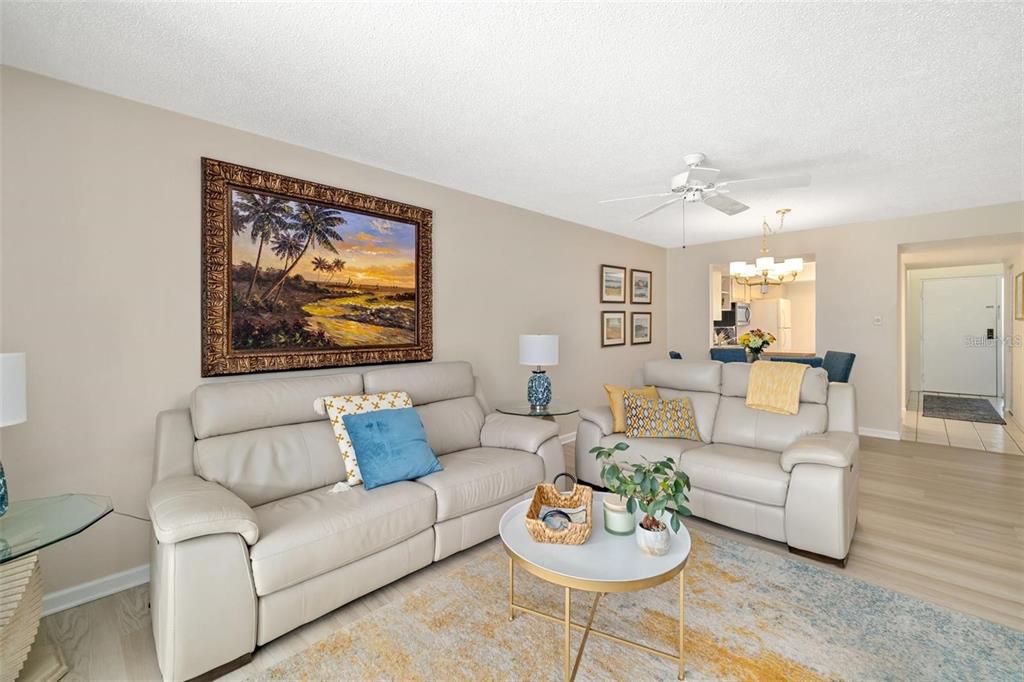 A living room with two light-colored sofas, a round coffee table, and a large painting — 7201 CURTISS AVENUE UNIT 2D, SARASOTA, FL
