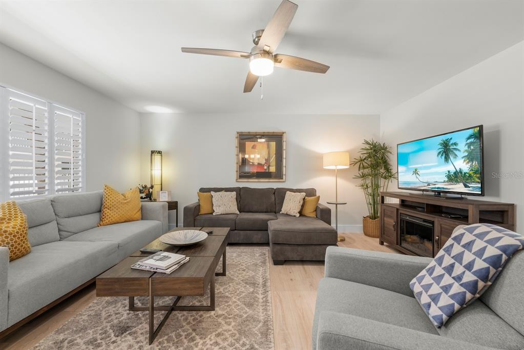 A living room features a grey sectional, a sofa, an armchair, and a television console — 624 FLAMINGO DRIVE UNIT 112, VENICE, FL