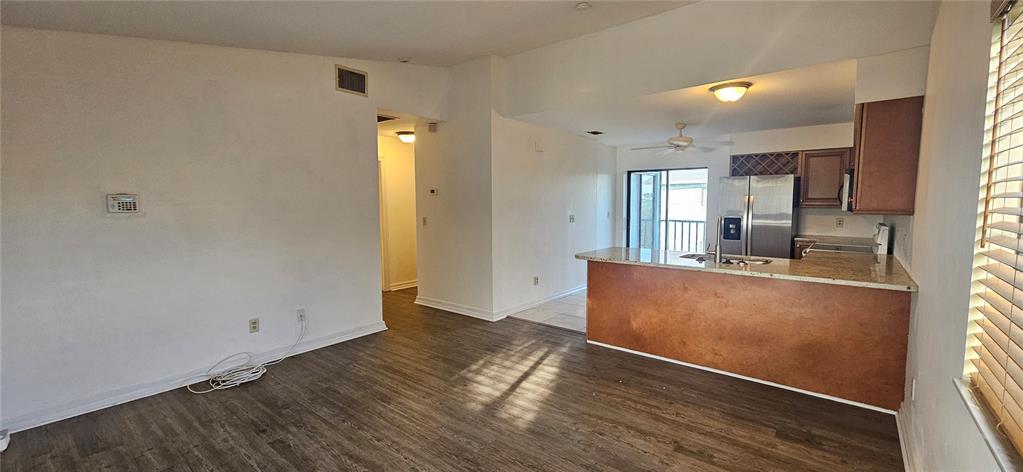 An open-concept living area features wood-look flooring, a kitchen island, and stainless steel appliances — 4904 VINCENNES COURT UNIT 209, CAPE CORAL, FL