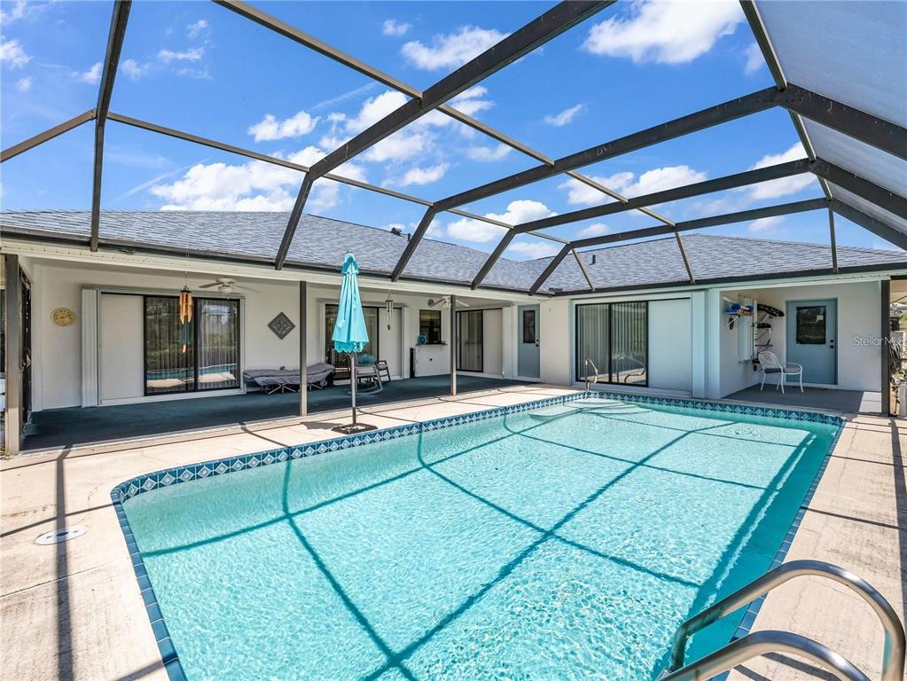 A swimming pool sits inside a screened-in lanai attached to a single-story house — 6170 DAVID BOULEVARD, PORT CHARLOTTE, FL