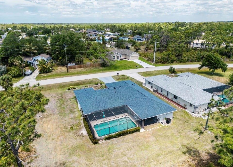 An aerial view shows a house with a blue roof and a screened-in swimming pool — 6170 DAVID BOULEVARD, PORT CHARLOTTE, FL