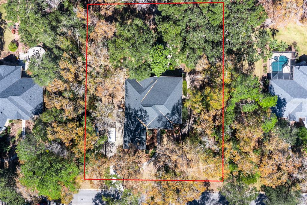 An aerial view shows a house with a dark roof surrounded by dense trees — 10320 SW 17TH PLACE, GAINESVILLE, FL